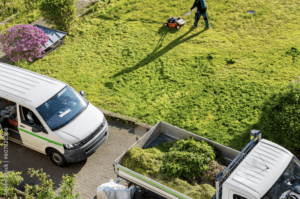 Aerial shot of a fleet of municipal parks & recs vans outside of a park with a city worker mowing grass